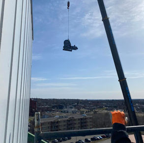 Worker lifting heavy equipment with the help of crane