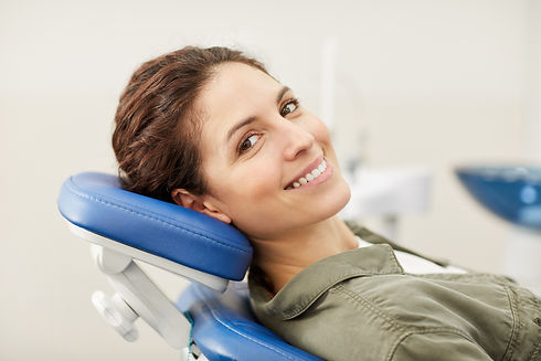 Portrait d'une jeune femme souriante allongée dans un fauteuil dentaire