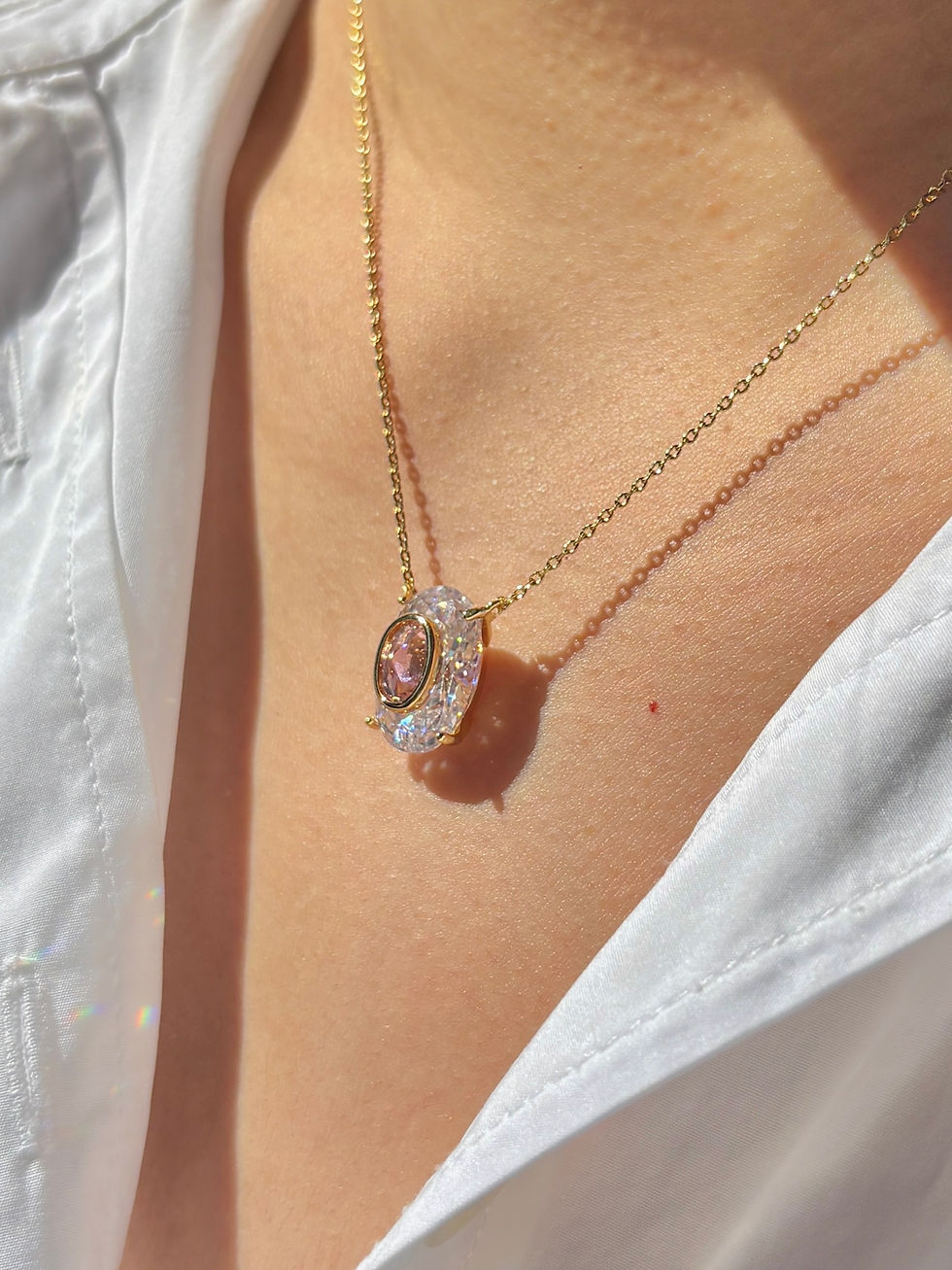 Thumbnail: Model wearing a vintage oval pink crystal pendant necklace with a delicate gold chain detail of statement pendant necklace