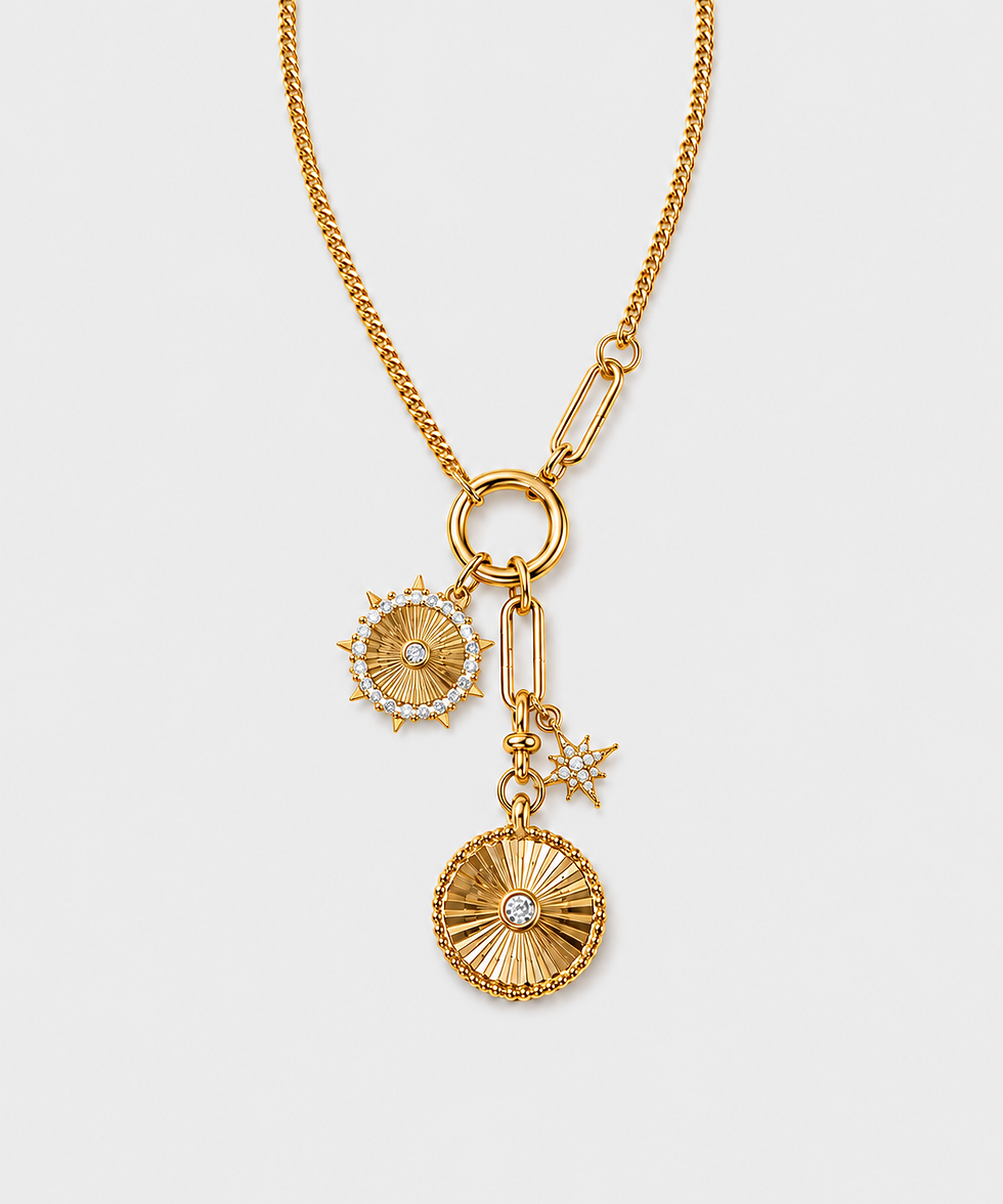 Gold charm necklace close-up with two sunburst coin pendants, crystal accents and a star charm on a light gray background.