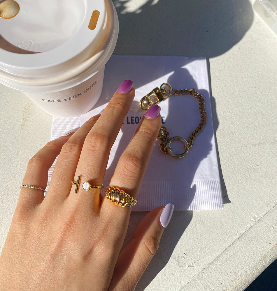 Thumbnail: A take out cup of coffee and a hand full of gold jewelries includes gold croissant ring