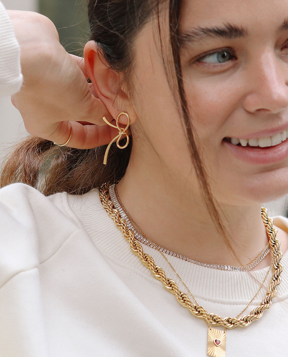 A high level gold plated bow ribbon earring and gold necklace on a person