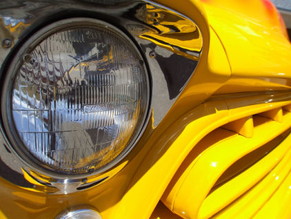the headlight and front grill of a yellow, 1957 Chevy 3100 pickup.
