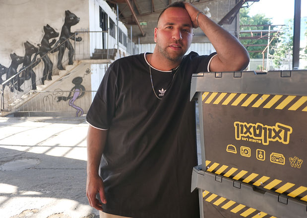 עומר חביב נשען על קופסאות עם הלוגו של דאוןטאון