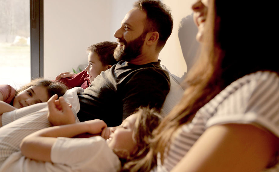 Family laughing together on a couch, reflecting the confidence that comes from investment and retirement strategy services by SummitPoint Capital Management.