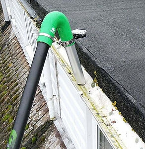 Gutter vacuum with pole sucking the dirt from a white UPVC gutter.