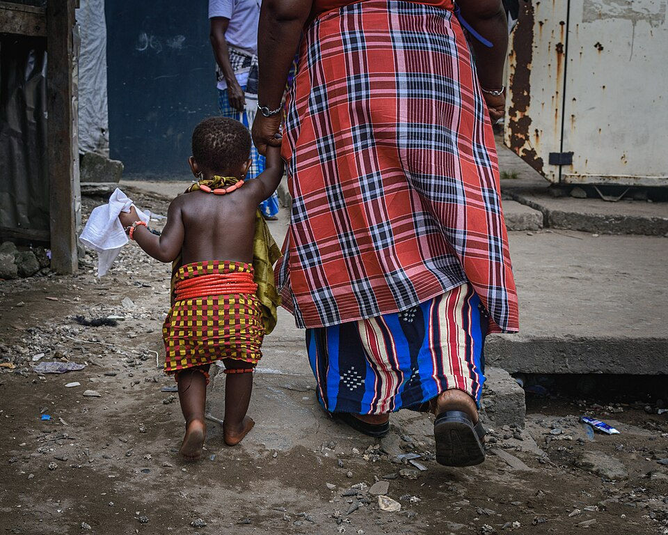 Woman_walking_with_child_dressed_as_Iriabo_during_Agiri_Festival_Bille_Kingdom_Rivers_Stat