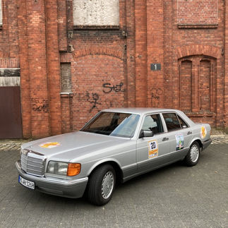 Silberner Mercedes-Benz vor Backsteinwand