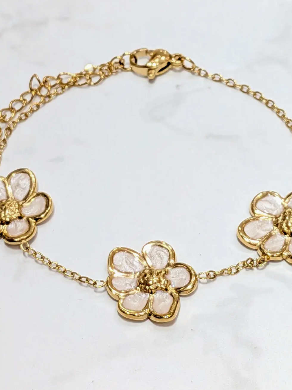 Goldfarbenes Edelstahl Armband mit drei elfenbeinfarbenen Blütenelementen, zartes Damen Blumenarmband