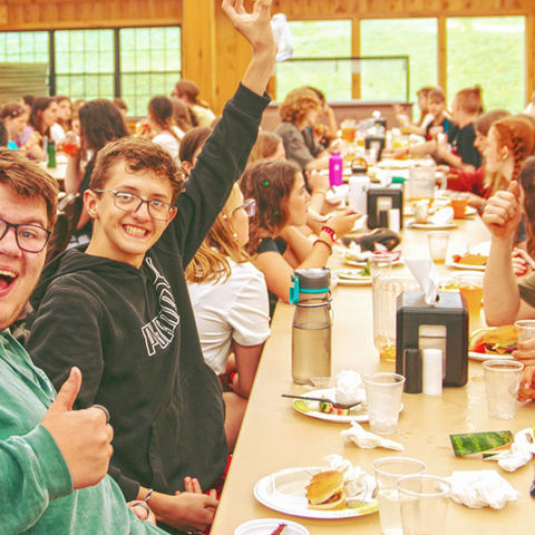 Camp counselors eat with campers at the dining hall