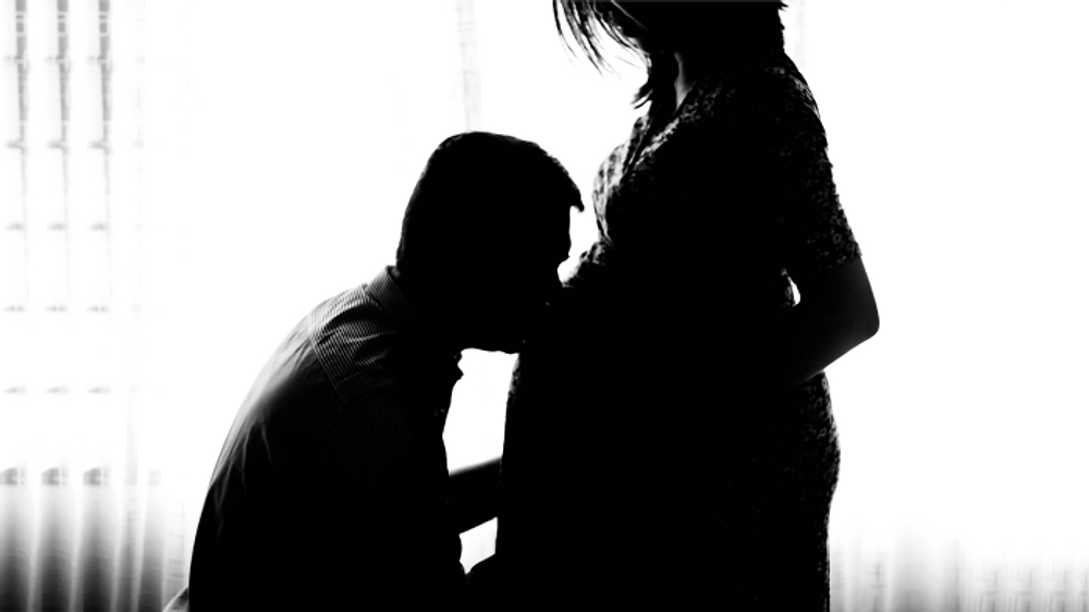 husband kissing pregnant wife showing support through in vitro fertilization