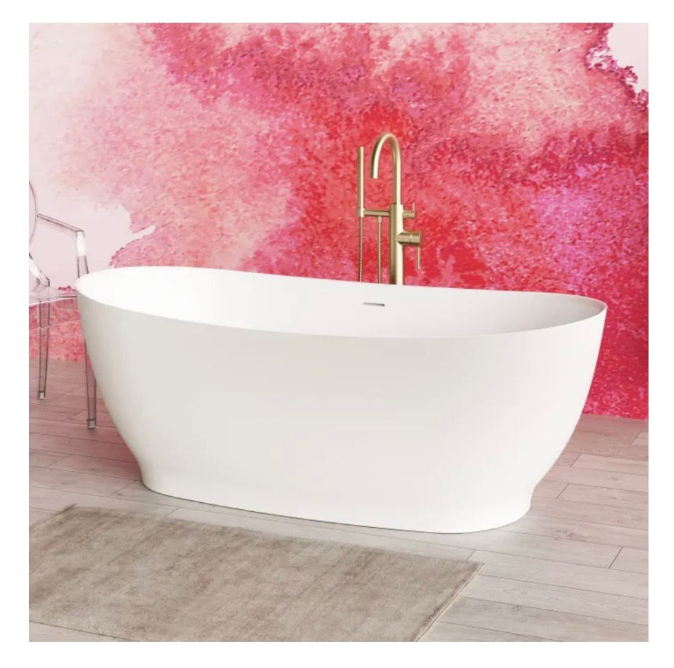 A beautiful white bathtub in front of a contemporary red wall