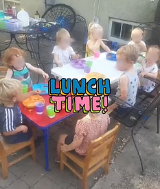 Children having lunch outdoors at a table.