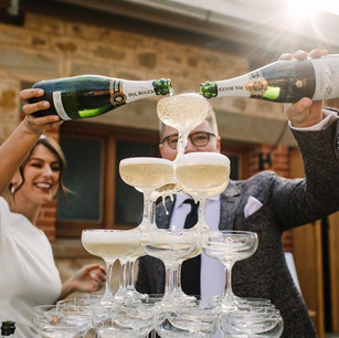 a couple pouring champagne onto a tower of glasses in adelaide