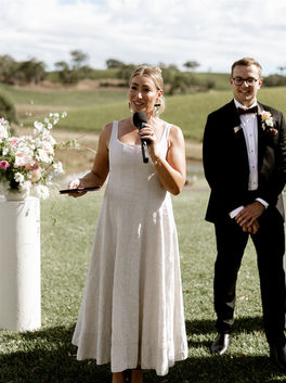 A celebrant wearing a cream dress talking into a microphone