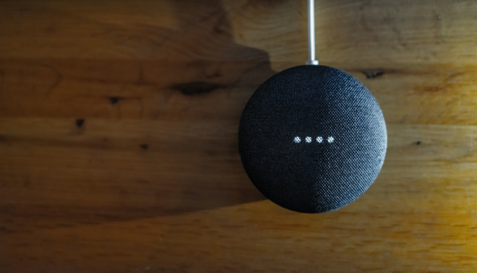 Smart speaker on wooden surface, displaying lights, waiting for command.