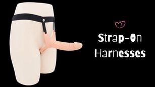 Mannequin wearing a strap-on harness with a dildo against a black background. Text reads "Strap-On Harnesses" with a heart icon.