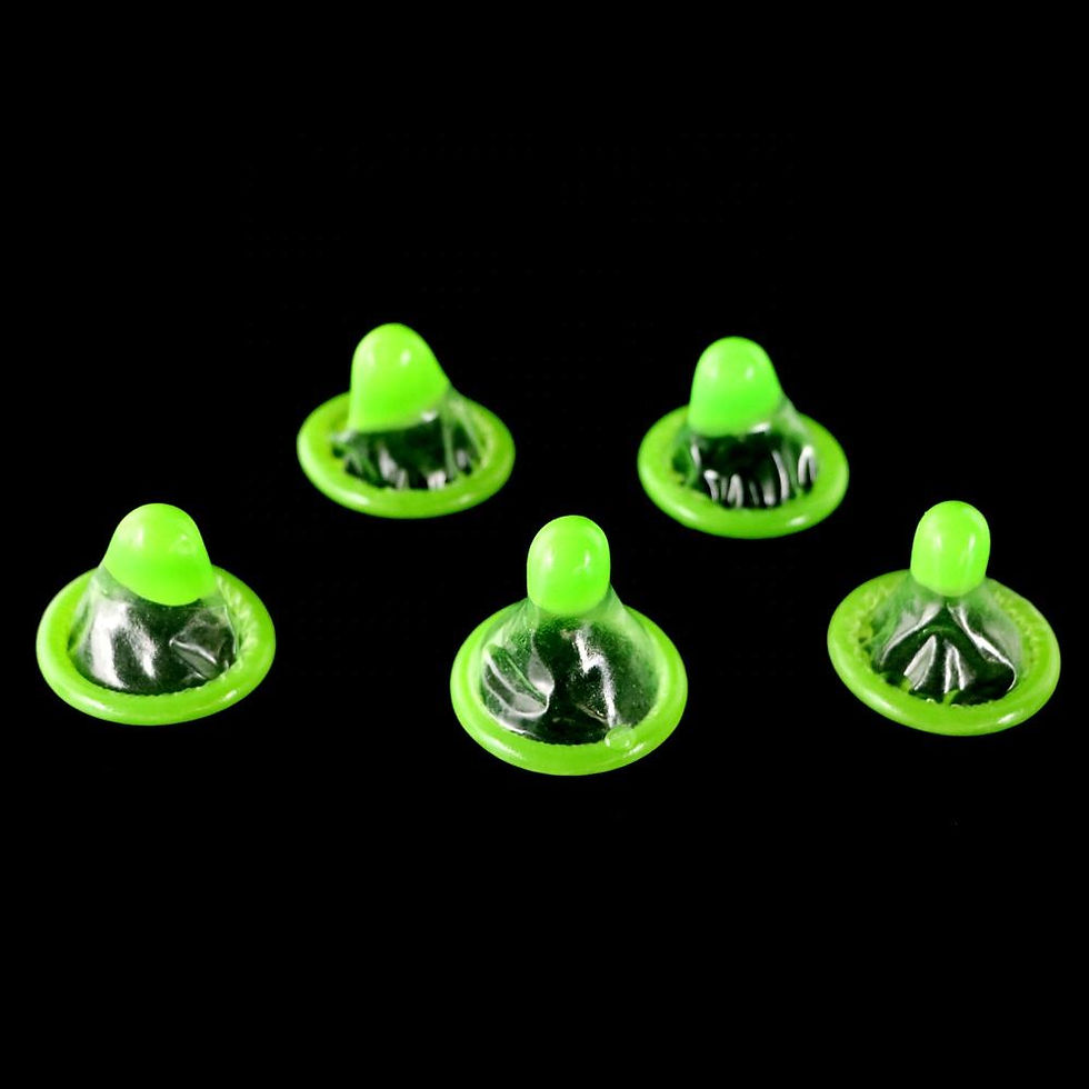 Five green glow in the dark condoms are arranged on a black background. They are unrolled, with tips pointing upward, creating a vivid contrast.