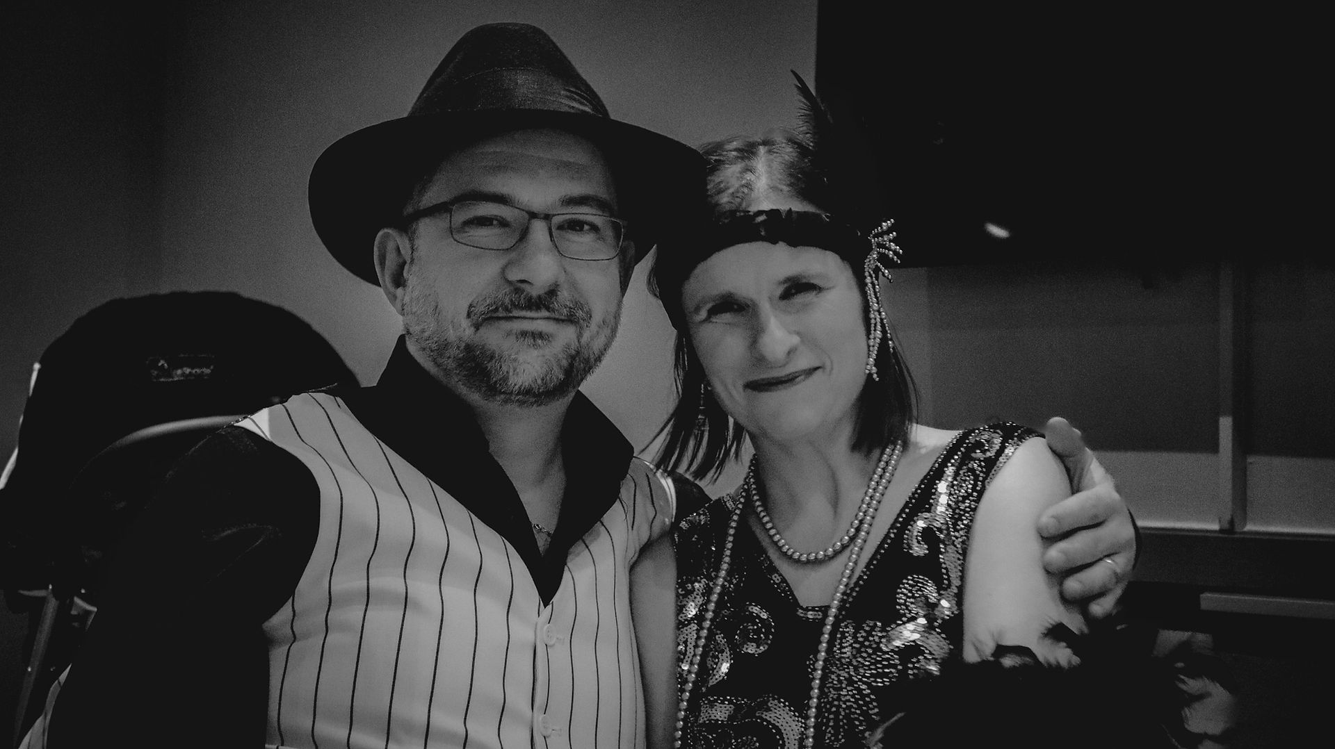 Black-and-white photo of two HandyCon 15 attendees dressed in stylish Noir-themed costumes, embracing the vintage atmosphere of the board game convention's special event.