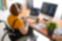 Female freelance programmer in modern headphones sitting in wheelchair and using computers