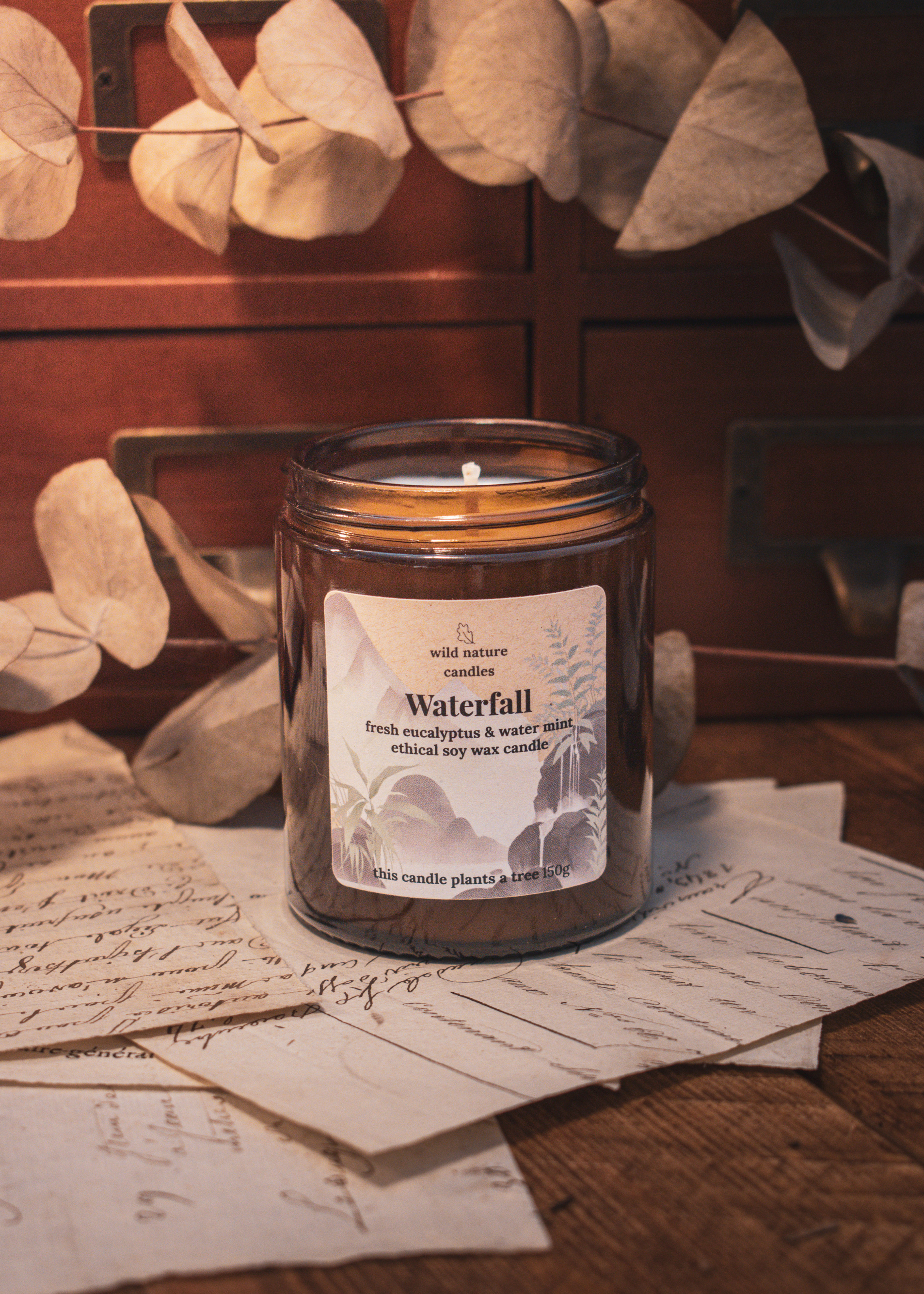 Waterfall soy candle styled with handwritten paper, wooden drawers and dried eucalyptus, fresh water mint home fragrance