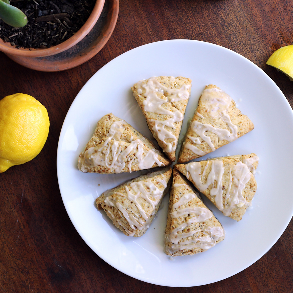 Flaky lemon poppy seed sourdough scones on parchment paper with golden edges and a lemon wedge garnish