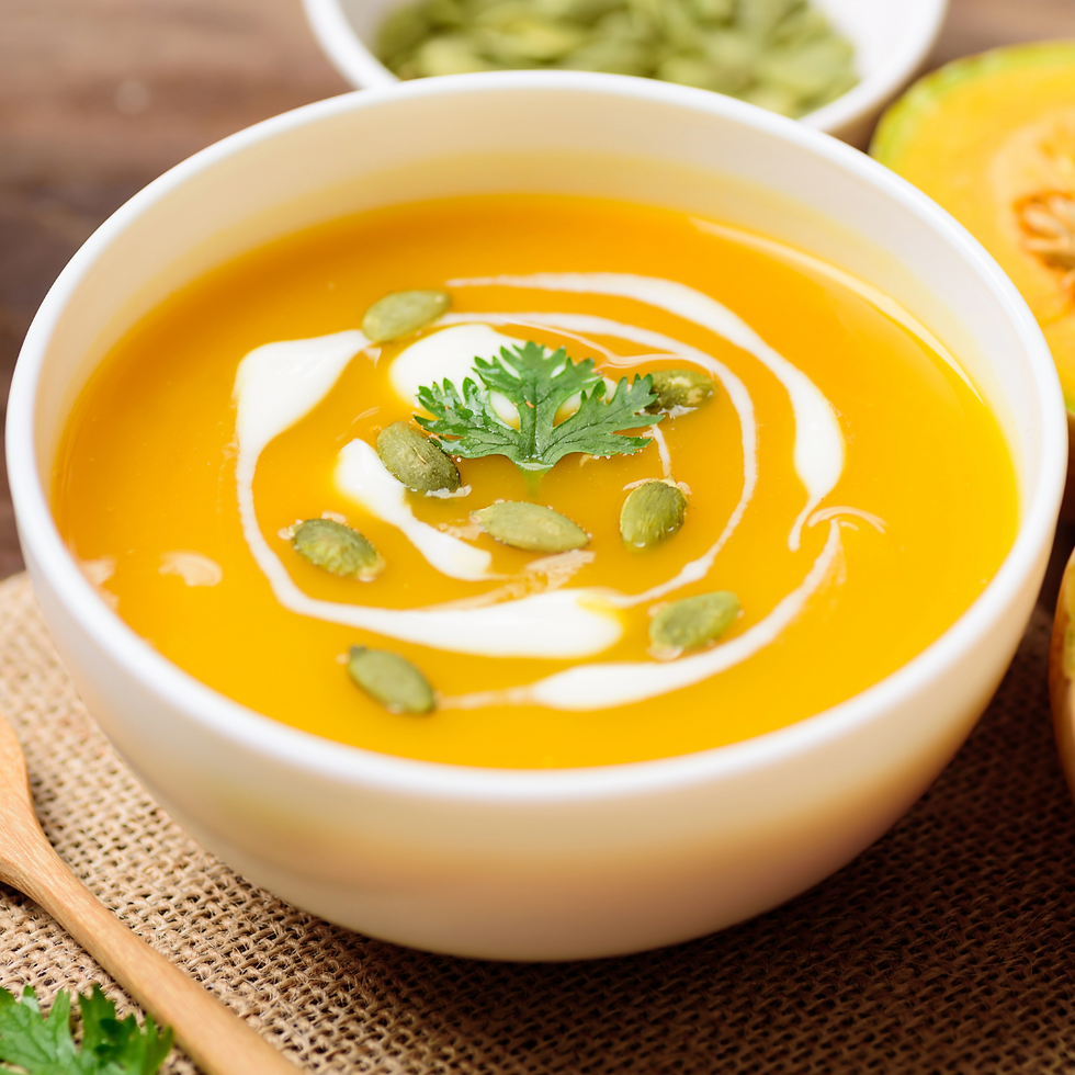 Bowl of golden pumpkin and corn soup garnished with herbs.