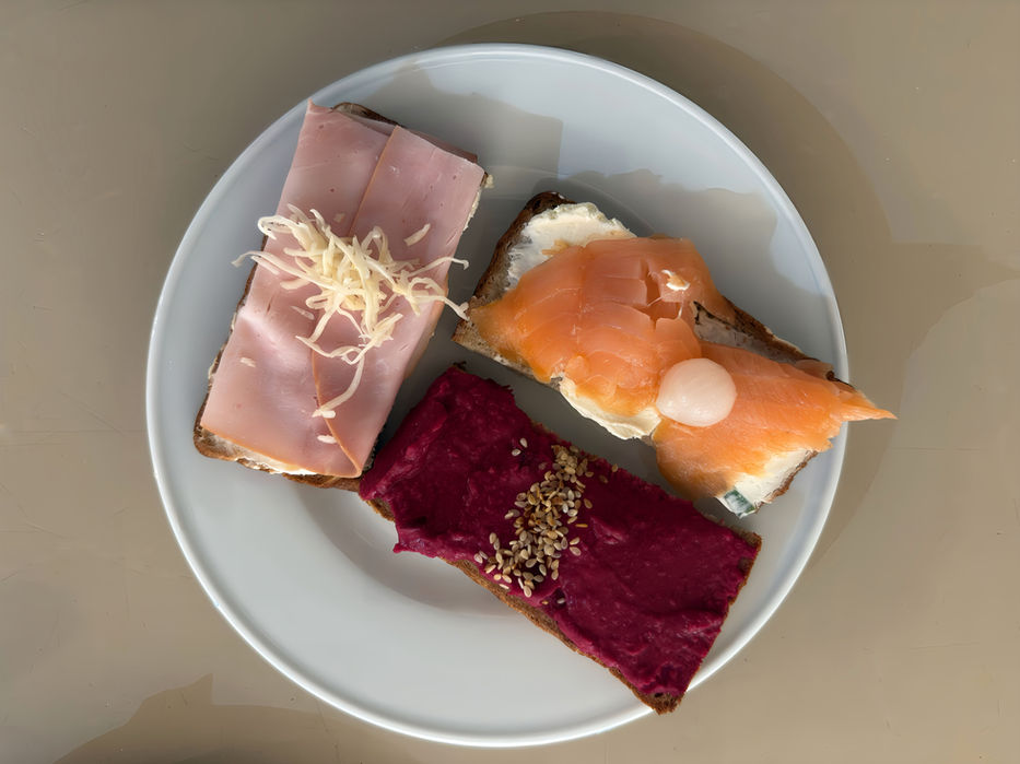 Drei belegte Brote auf einem Teller mit Lachs, Schinken und Rote Bete.