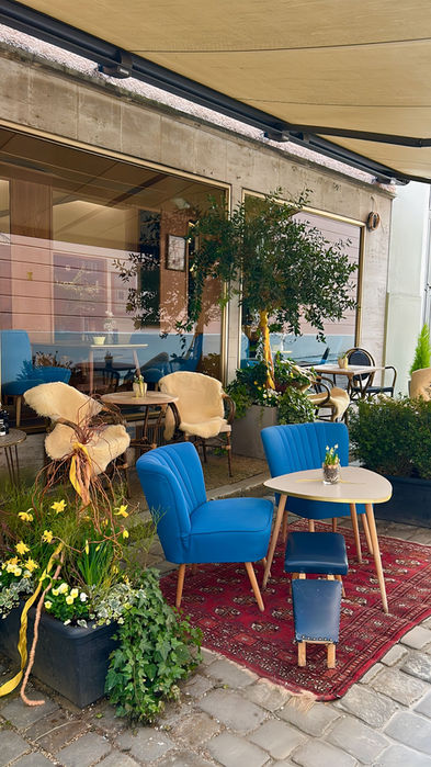 Blaue Stühle und Tische draußen beim Cafe Schöffberger, gemütliche Atmosphäre mit Pflanzen.