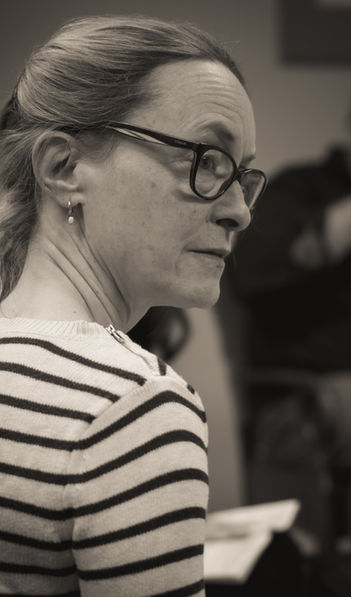 A photo from rehearsals for the play, "God of Carnage." One of the actors sits in the foreground, looking off-stage.