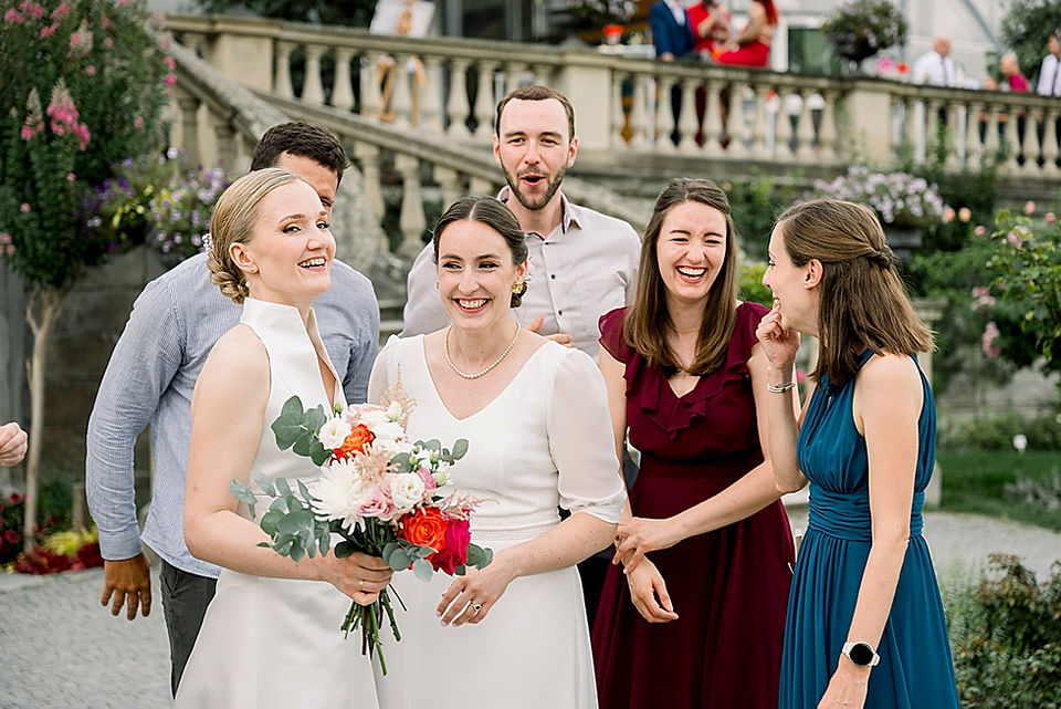 Brautpaar mit Freunde lacht an der Hochzeitsfeier auf der Insel Mainau