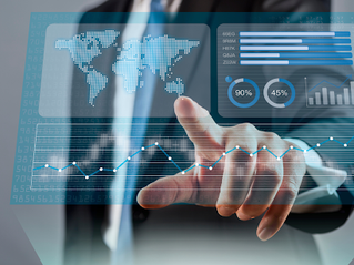 A person in a suit interacts with a virtual screen displaying global maps, graphs, and data analytics in blue tones.