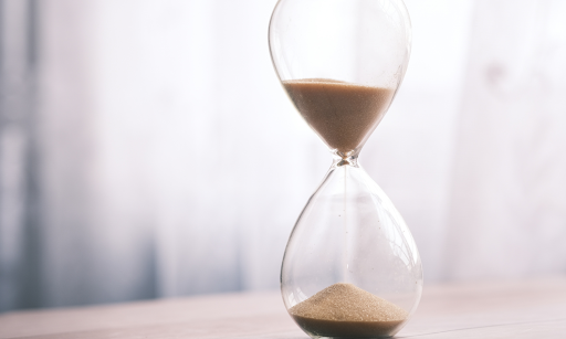 Close-up of a glass hourglass with sand running through, symbolising the countdown to financial deadlines or EOFY tax planning urgency.