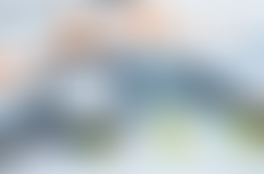 Magnifying glass and pen on colorful financial graphs and charts, showing various data and expenses. Blue, orange, and green hues.