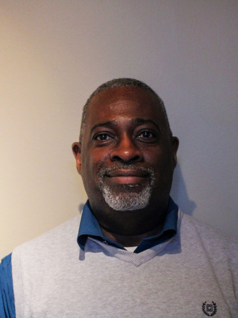 a man wearing a sweater with very shirt black/gray curly hair.