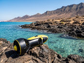 Person exploring underwater with a sea scooter in clear ocean water