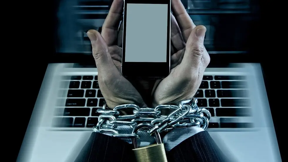 Eller zincirli, kilitli biri telefon tutuyor. Arka planda bir laptop bulunuyor. Karmaşık ve endişeli bir atmosfer hissediliyor.