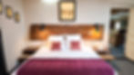 Chambre de la suite familiale Prével avec grand lit et décoration chaleureuse.