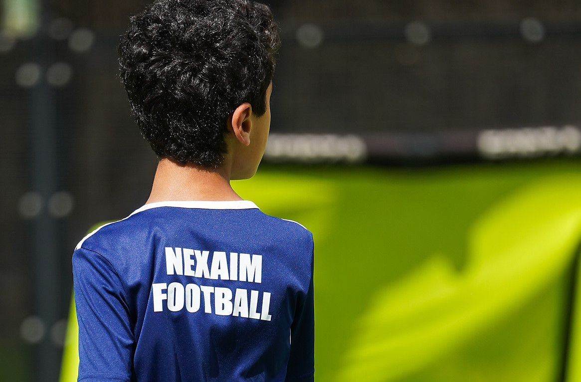 Young football player wearing a NexAim Football shirt walking on a training pitch during a kids coaching session