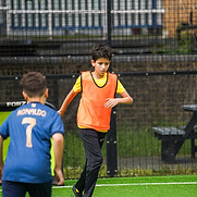 NexAim Football player in an orange training bib dribbles confidently during a small-sided game.