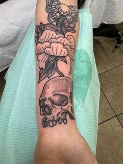 Skull tattoo in black and gray with other artwork
