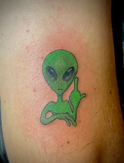 A green alien swearing on an arm, created by a fort worth tattoo artist