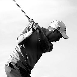 golfer in black and white swinging a golf club during competition
