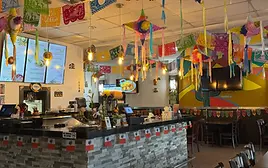 Interior of Auténtica Taquería in Miami featuring colorful papel picado, hanging piñatas, 