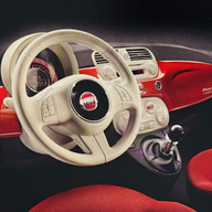 Interno del concept Fiat Trepiùno visto in prospettiva laterale, con in evidenza la plancia minimalista, il volante compatto, i sedili chiari e l’idea di uno sfruttamento intelligente dello spazio interno in un’auto urbana dalle dimensioni contenute.