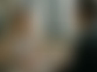 Psicóloga organizacional em conversa empática com um colega de trabalho em um escritório moderno e iluminado por luz natural. Ela está sorrindo levemente, com as mãos unidas sobre a mesa, transmitindo calma, atenção e equilíbrio emocional. A cena simboliza escuta ativa e inteligência emocional no ambiente corporativo.