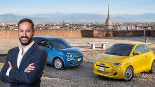 Montagem editorial com Carlos Adán, diretor de Comunicação da Fiat, em primeiro plano, diante de dois Fiat 500 Hybrid nas cores azul e amarelo, com a cidade de Torino e a Mole Antonelliana ao fundo.