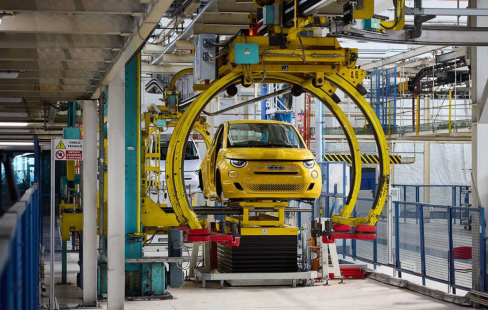 FIAT 500 em Mirafiori, modelo amarelo em processo de montagem na linha de produção da fábrica de Torino, suspenso por equipamento industrial circular dentro do complexo fabril moderno.