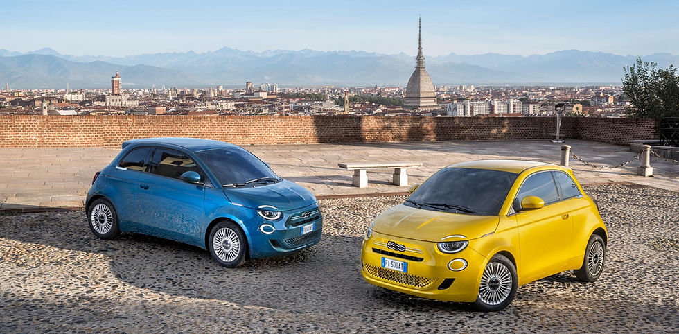 Em um mirante de Torino a imagem tem dois Fiat 500 Hybrid estacionados , um azul e outro amarelo, com a cidade ao fundo e a Mole Antonelliana em destaque, os dos carros representam o design italiano, herança urbana e identidade local.