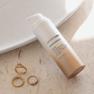 Picture of nourishing regenerative cream balancing on the side of a glass plate with gold finger rings beside it. 
